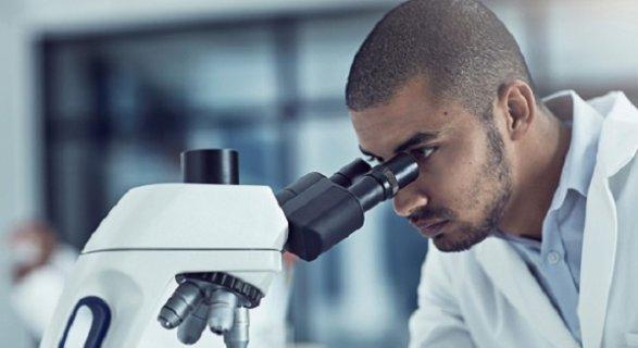 Man looking down microscope 