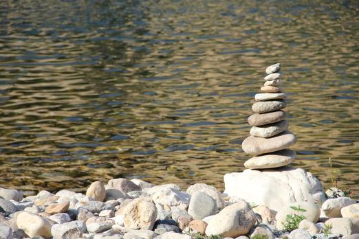 A pile of stones sits alongside a river bank