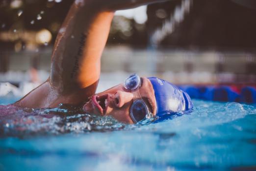 person swimming in goggles and swimming hat