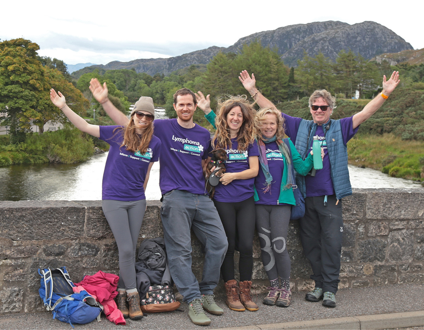 Group of walkers cheering on bridge wearing purple t-shirts