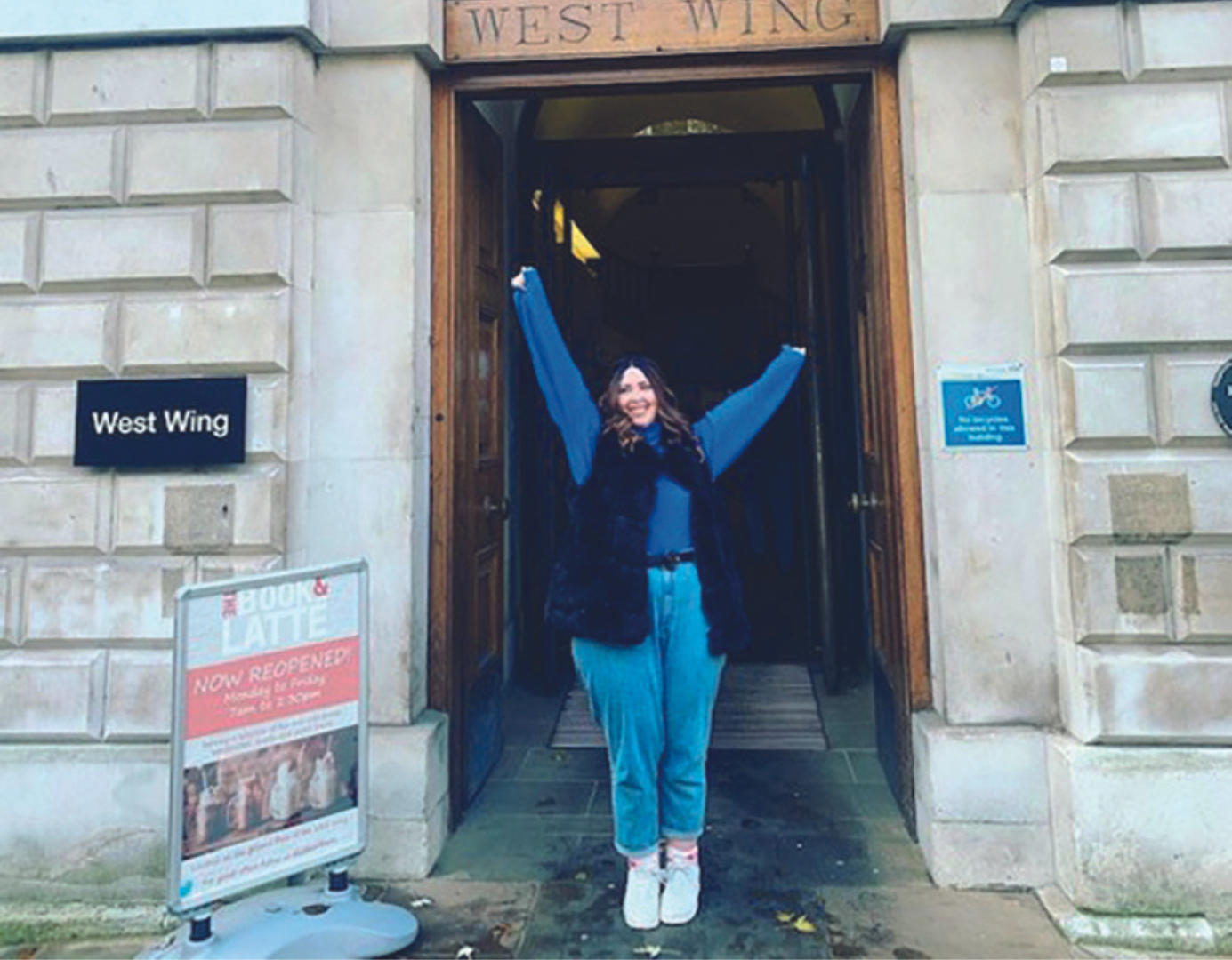 Young woman standing outside hospital wing celebrating