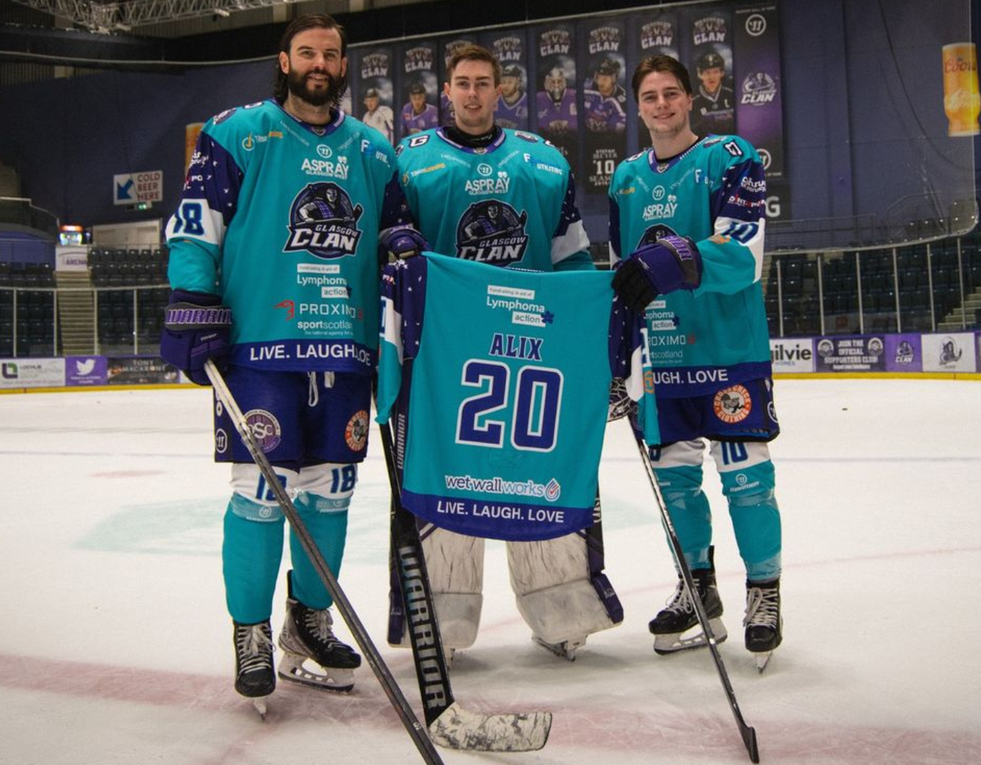 Three male ice hockey players holding up Lymphoma Action sponsored shirts