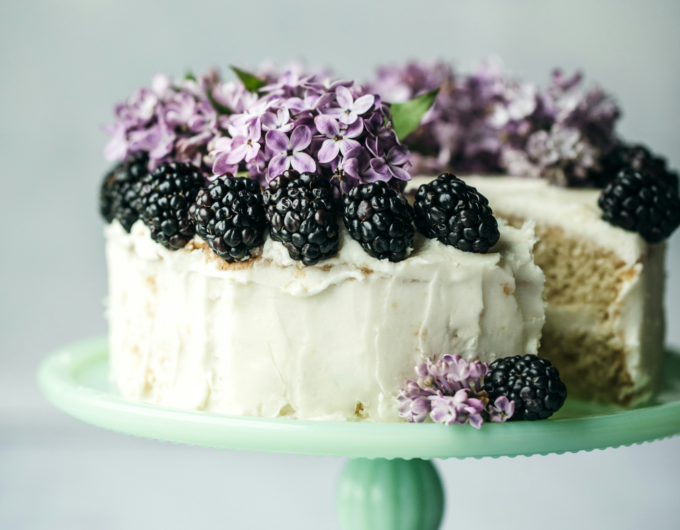 Sponge cake decorated with blackberries and purple flowers