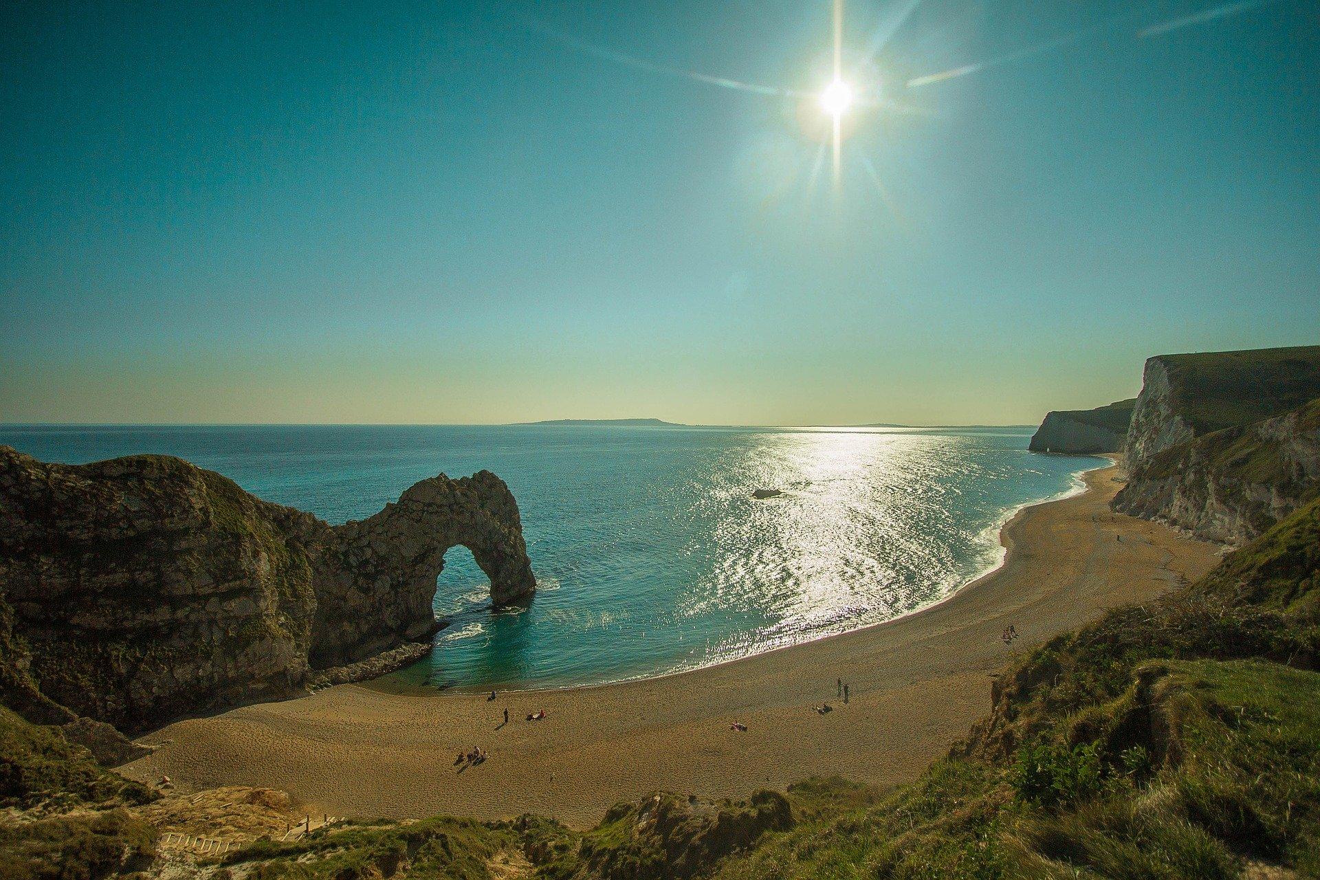 Sandy beach with blue sea and blue sky and shining sun