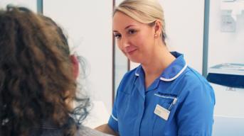 A nurse in a blue uniform smiles at a patient