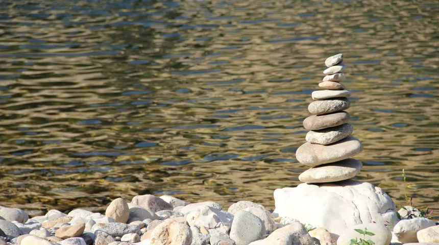 A pile of stones sits alongside a river bank