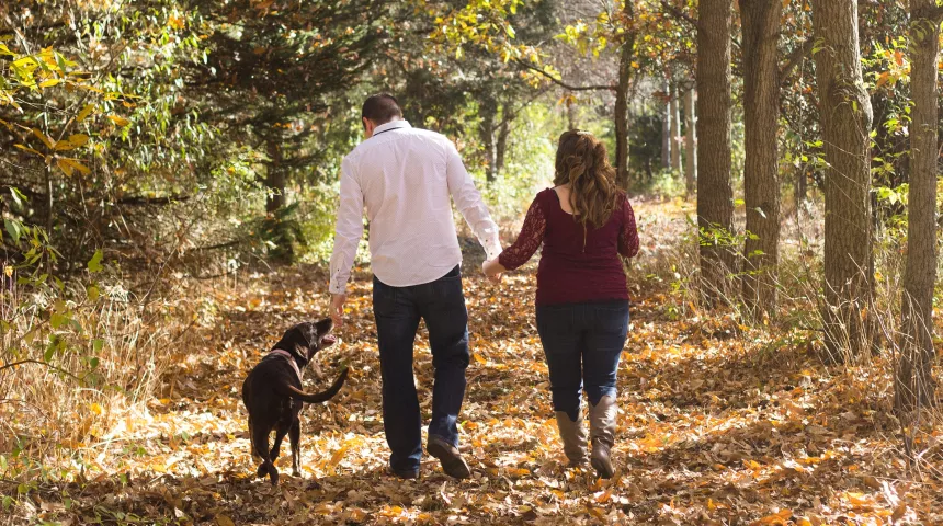 A man, woman and dog walking in the woods