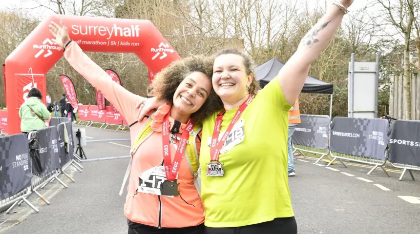 two runners with finishers medals at the surrey half marathon finish line