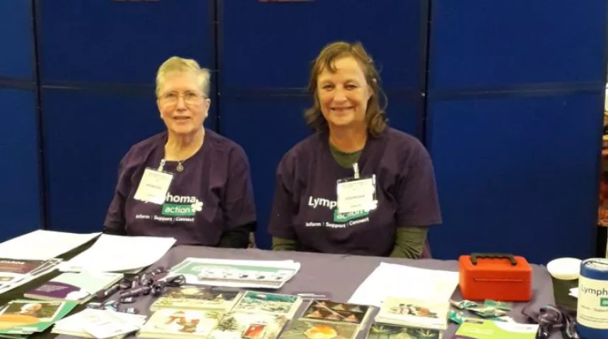 Image of two women sitting behind a Lymphoma Action stall smiling