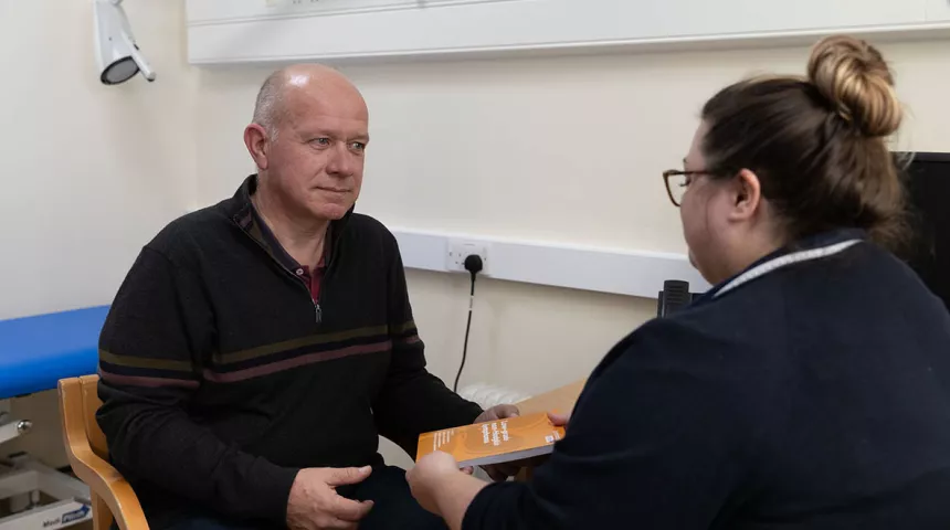 Nurse handing a man a Lymphoma Action book