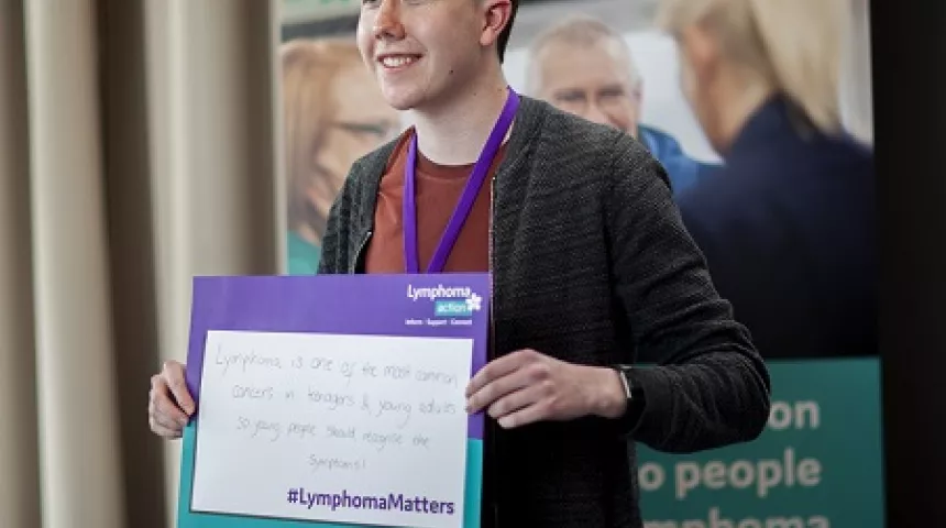 Callum holding a Lymphoma Matters poster 