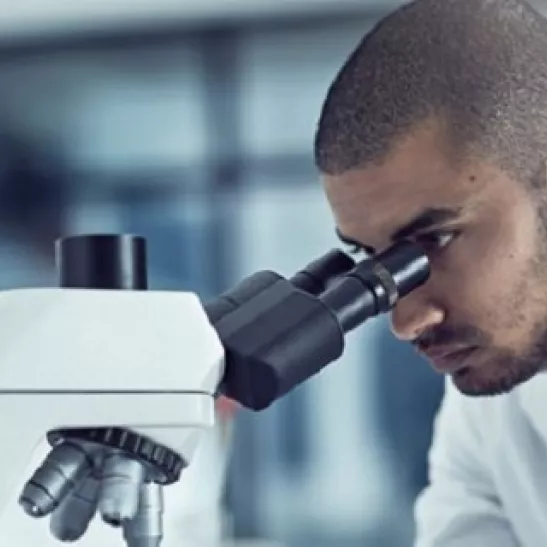 Man looking down microscope 