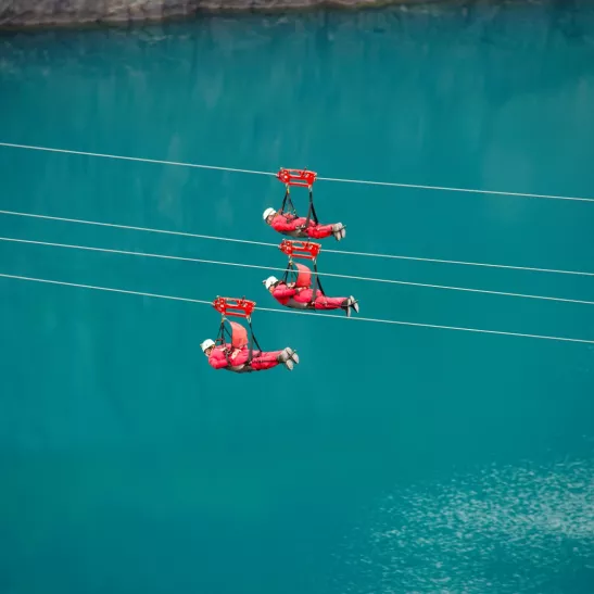 x3 people on zip line over water