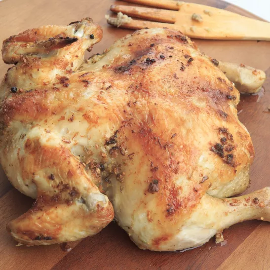 Cooked roast chicken on a wooden platter