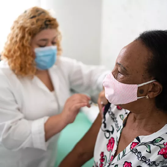 Person giving someone an injection wearing masks