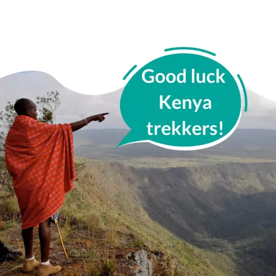 Lady stood on mountain pointing to speech bubble saying 'Good Luck Kenya Trekkers!'