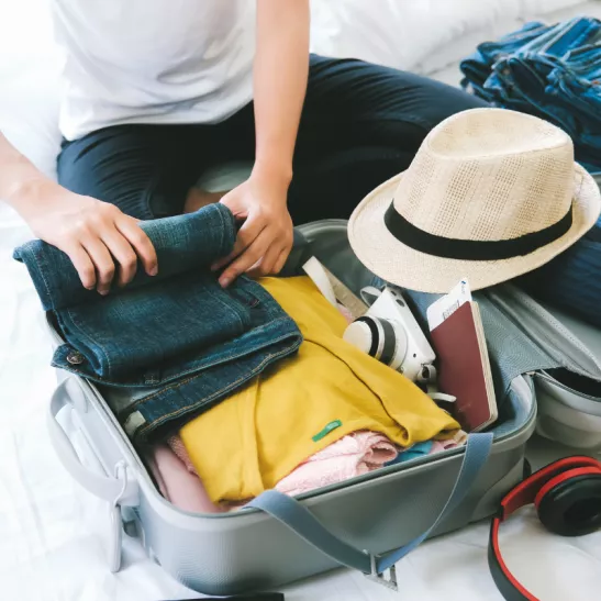 Person packing suitcase for a summer holiday