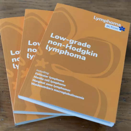 Image of 3 copies of the book - orange cover with white writing. Title is Low-grade non-Hodgkin lymphoma. Lymphoma Action logo in top right-hand corner