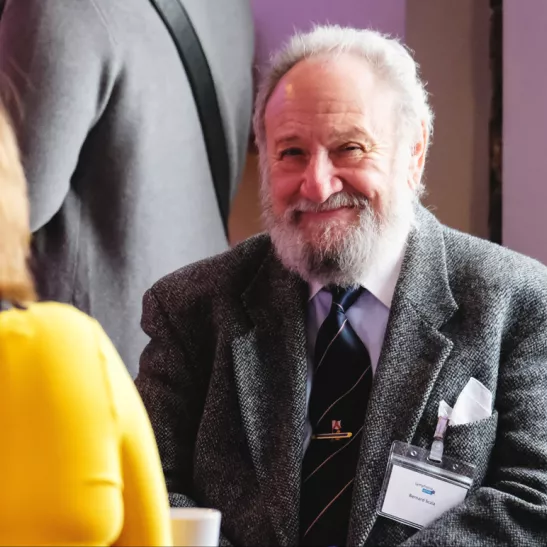 Man smiling as talking to a lady in yellow