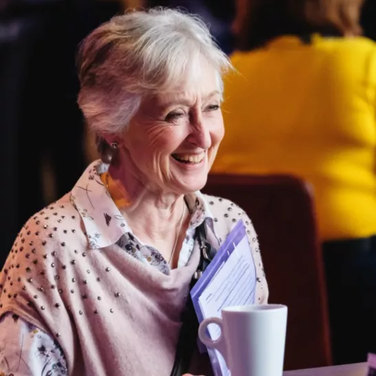 Lady with a cup of beverage smiling and chatting