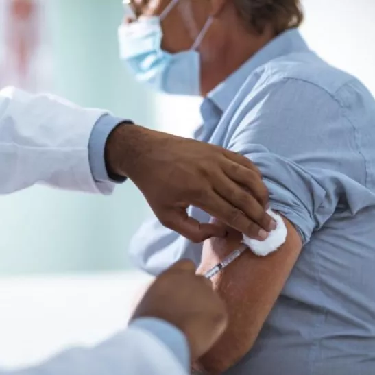 Image of a man receiving a vaccination in his left arm