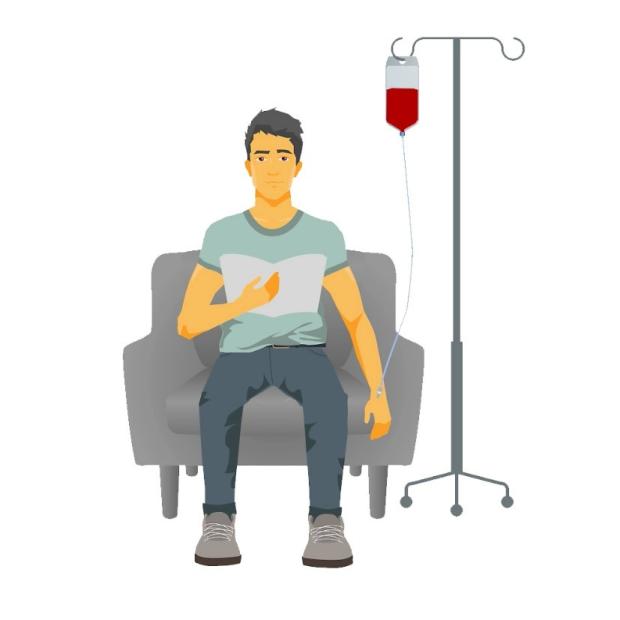 A man sitting in a chair, reading a book while having a blood transfusion. There is a tube going into his arm.